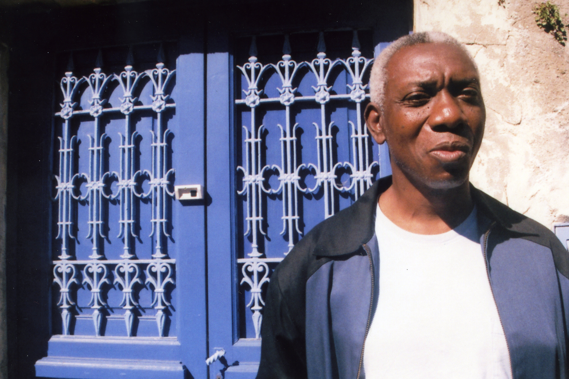 Photograph of Yusef Komunyakaa in front of a blue door.